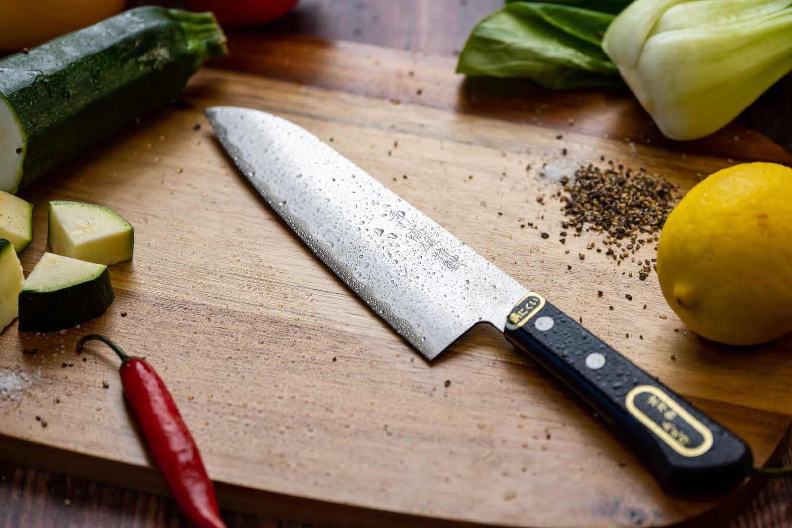 Japanese knife on a cutting board surrounded by vegetables